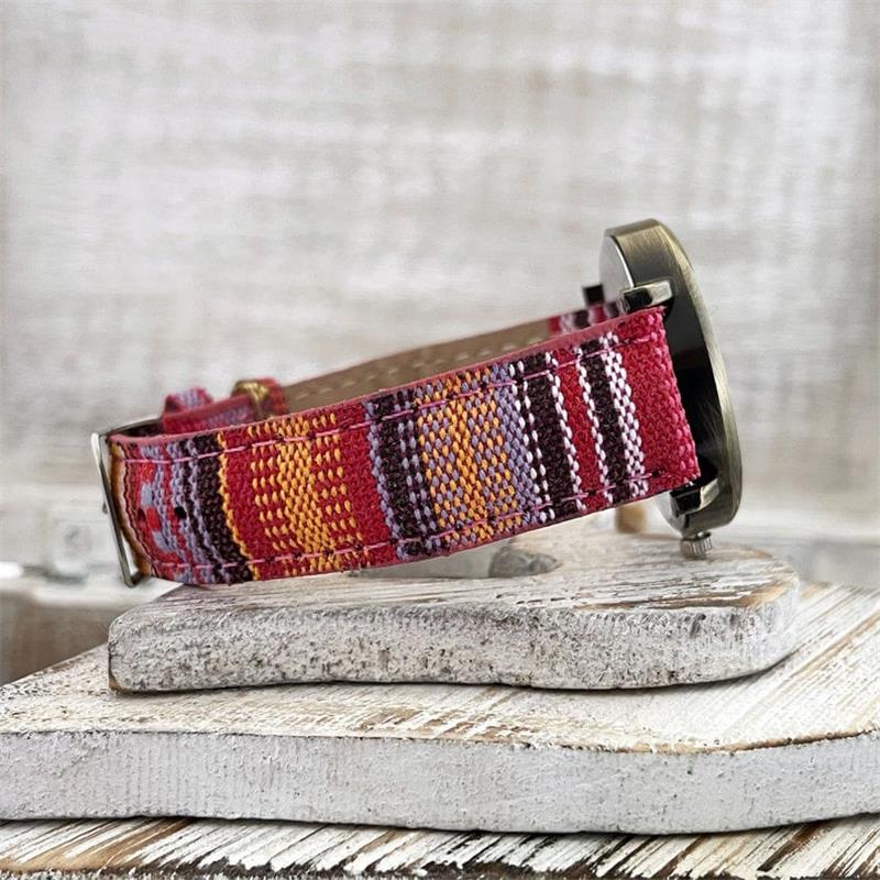 Close-up of a women's watch with a unique rainbow pattern face and an intricate braided strap design