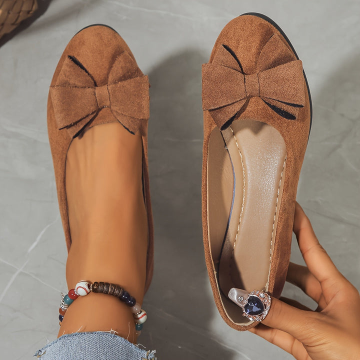 Black women's comfortable ballet flats with a wedge heel, slip-on design, and bow.