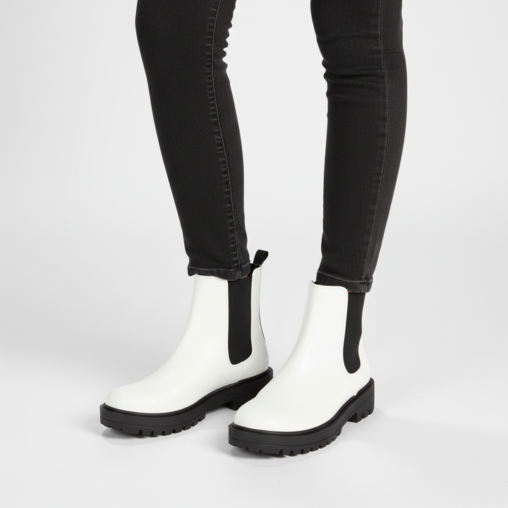 Women's black Chelsea ankle boots on wooden floor, showcasing autumn and winter style