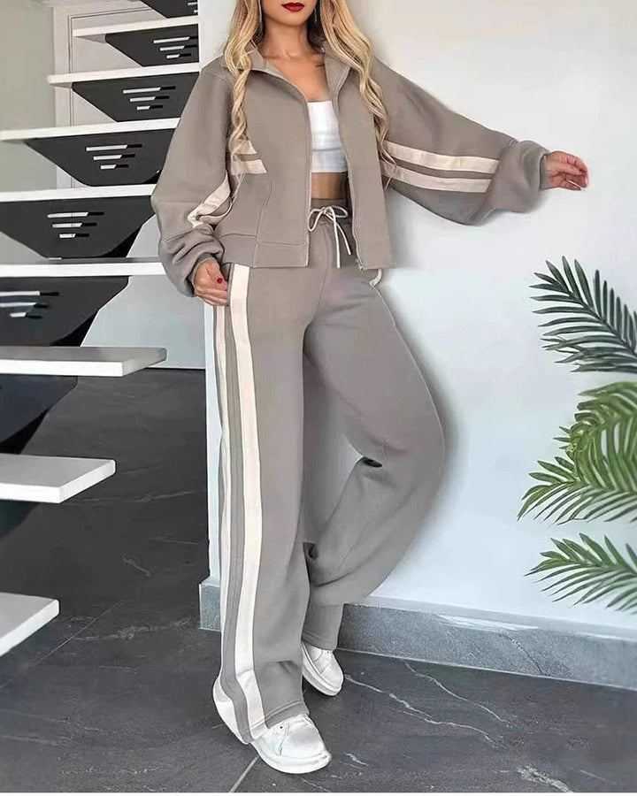 Soft women's lounge wear tracksuit set with a zip-up jacket & wide leg pants, featuring contrast stripes.