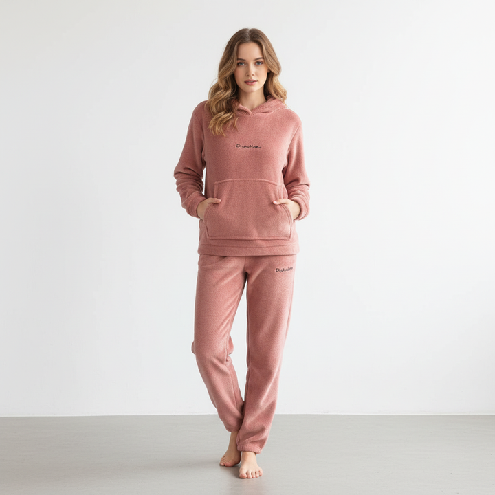 Woman relaxing at home wearing a comfy matching fleece hoodie and pants set.