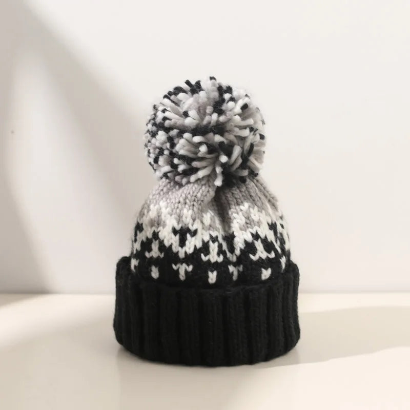 Women's cozy knitted winter beanie hat with white snowflake pattern & fluffy pom-pom.