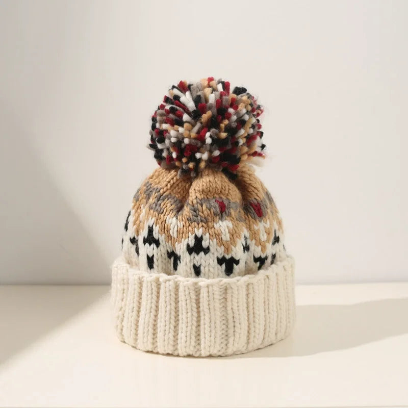 Cozy women's knitted beanie for cold weather, adorned with snowflake details & a pom pom.