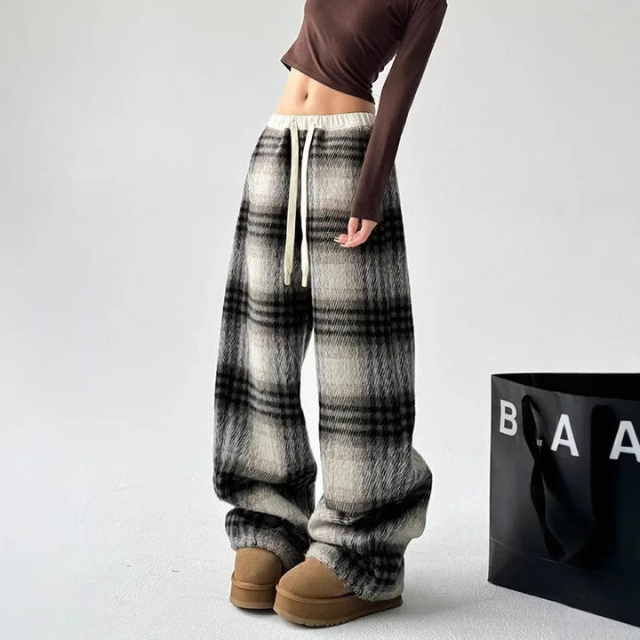 Woman relaxing in cozy plaid wide-leg lounge pants, ideal for home comfort and casual wear.
