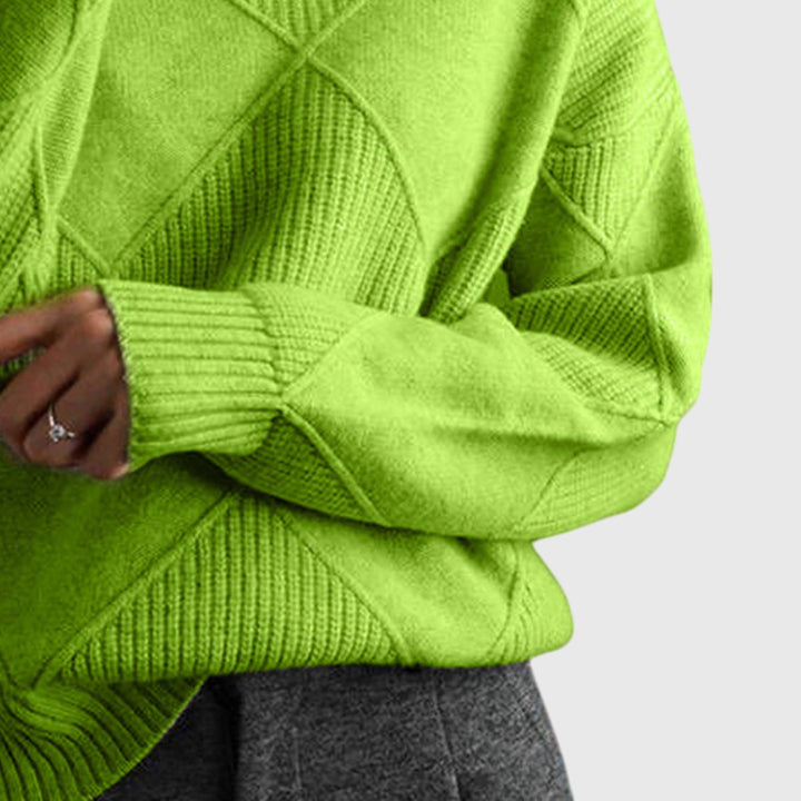 Woman comfortably seated in an oversized roll neck jumper, emphasizing warmth & coziness.