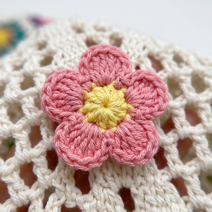 Close-up of a stylish women's crochet flower tote bag, featuring intricate floral patterns & a comfortable shoulder strap.