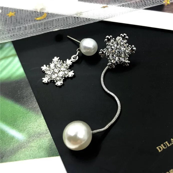 Close-up of elegant sterling silver dainty snowflake drop earrings, showing intricate winter charm design.