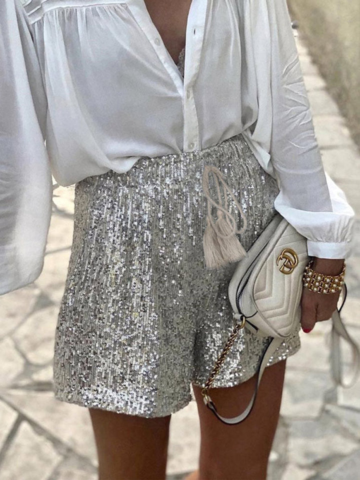 Close-up of shimmering silver sequin shorts. Intricate sequin detailing perfect for glamorous party fashion.