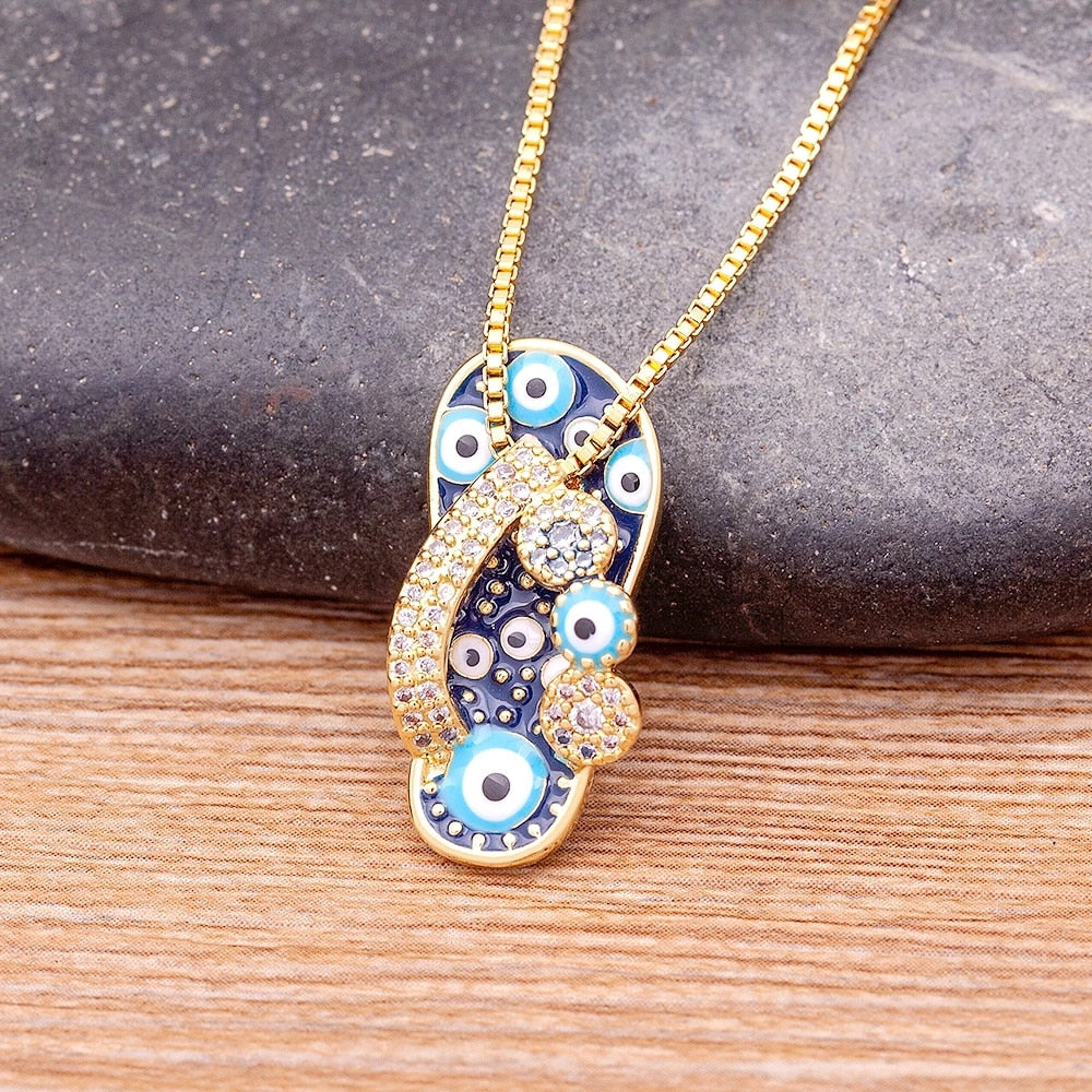Women's delicate gold necklace with a charming flip flop pendant and a protective evil eye charm, perfect for summer.
