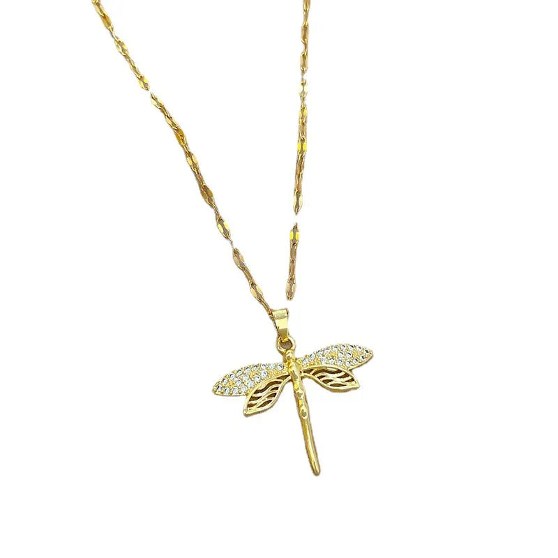 Close-up of a shimmering gold plated dragonfly pendant necklace for women, delicate and elegant.