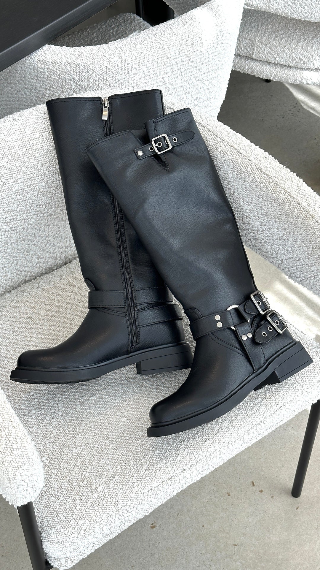 Fashionable women's black knee-high combat boots with an edgy design & multiple buckle details.