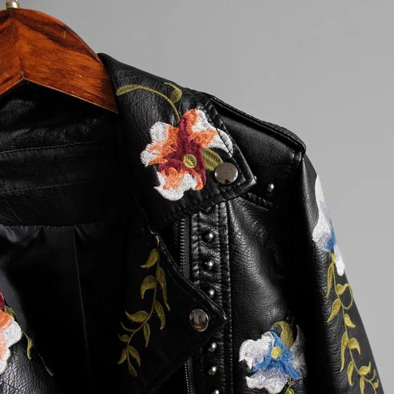 Bold studded detailing on an edgy women's black jacket featuring delicate floral embroidery.