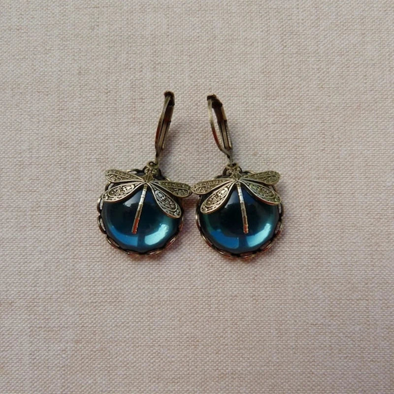 Close-up of intricate antique gold dragonfly earrings. Vintage, elegant nature-inspired women's jewelry.