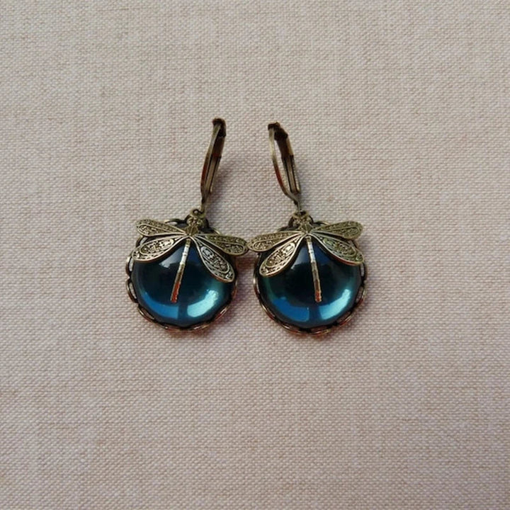Close-up of intricate antique gold dragonfly earrings. Vintage, elegant nature-inspired women's jewelry.