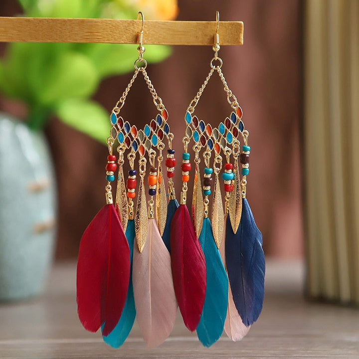 Boho-chic long feather dangle earrings for women. Statement fashion jewelry with a luxurious gold plated finish.