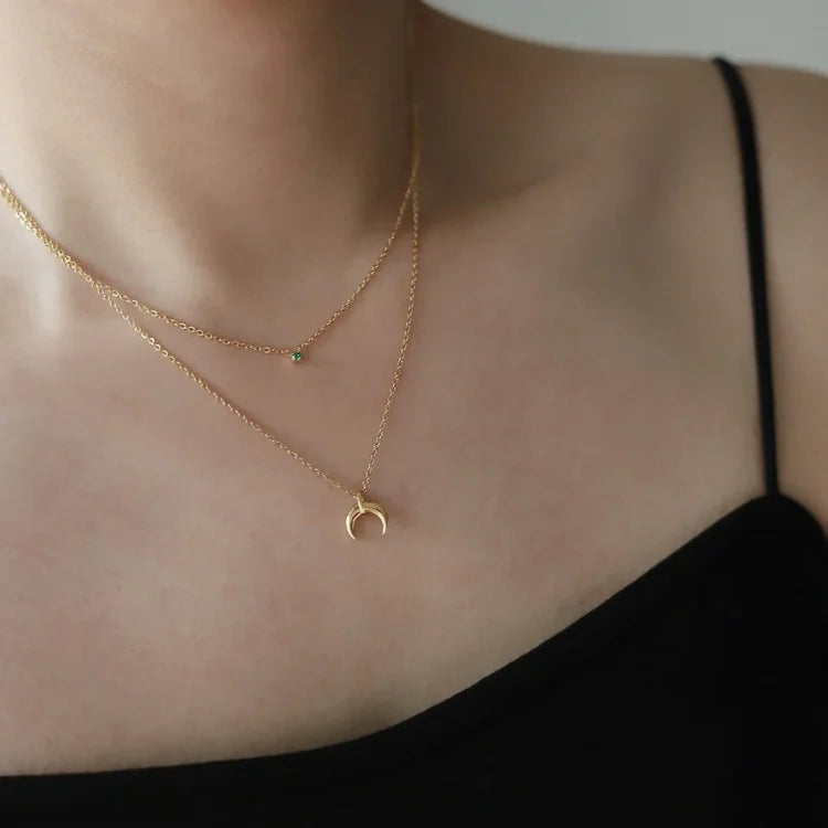 Sparkling green diamond double crescent moon necklace for women. A chic vintage style accessory.