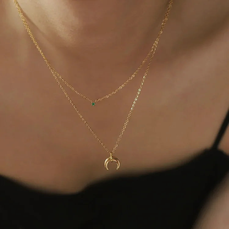 Close-up of a women's vintage style green diamond double crescent moon necklace. Elegant jewelry.