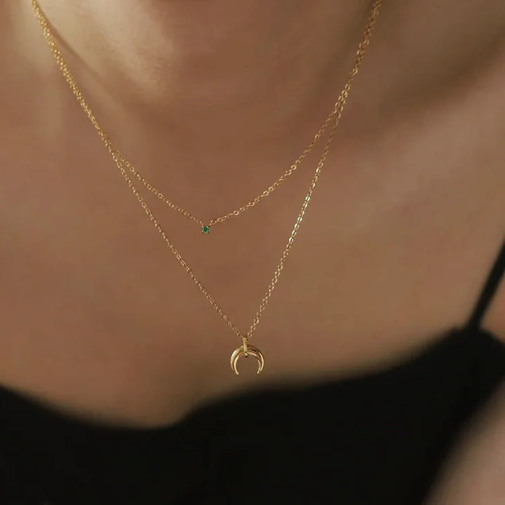 Close-up of a women's vintage style green diamond double crescent moon necklace. Elegant jewelry.
