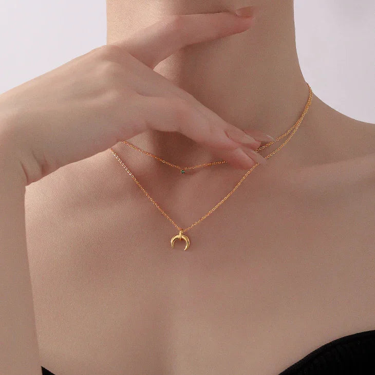 Layered women's necklace featuring two crescent moons with vibrant green diamonds. Elegant jewelry.