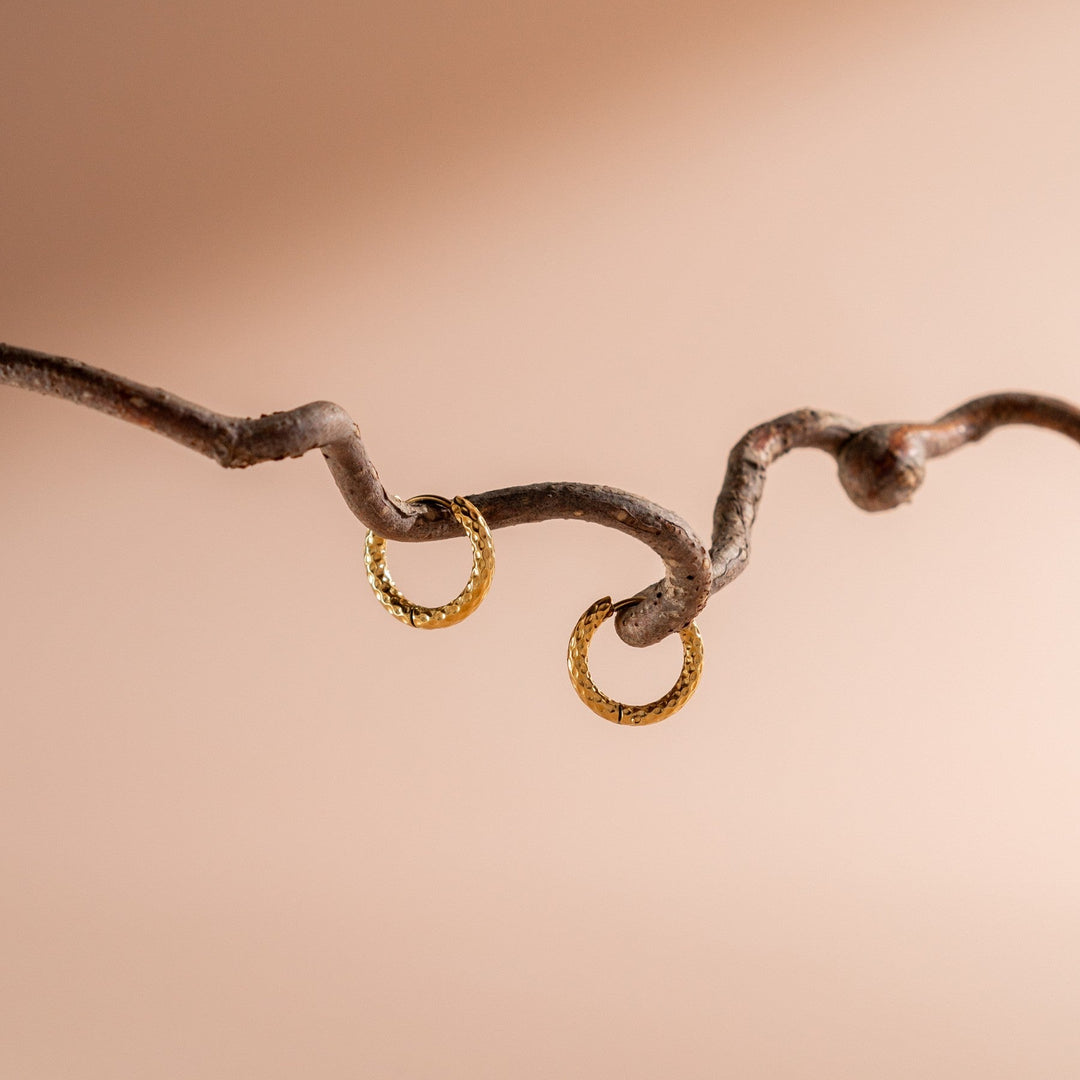 Close-up of women's hammered gold plated hoop earrings, showcasing unique texture & shine.