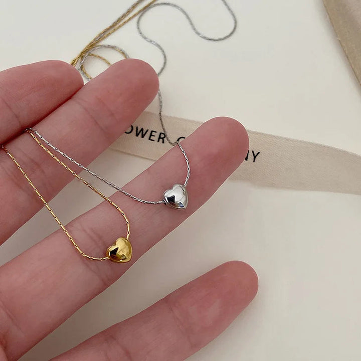 Close-up of a sleek minimalist heart necklace for women, elegant stainless steel, perfect dainty accessory.