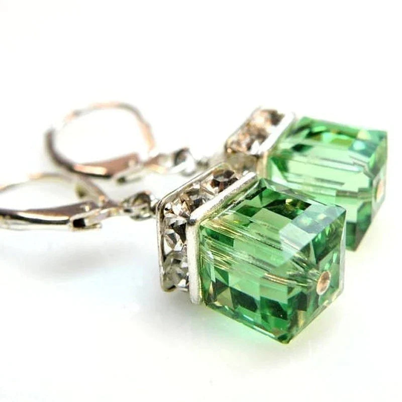 Close-up of sparkling peridot crystal drop earrings. Elegant green gemstone dangle earrings for women's jewelry collection.