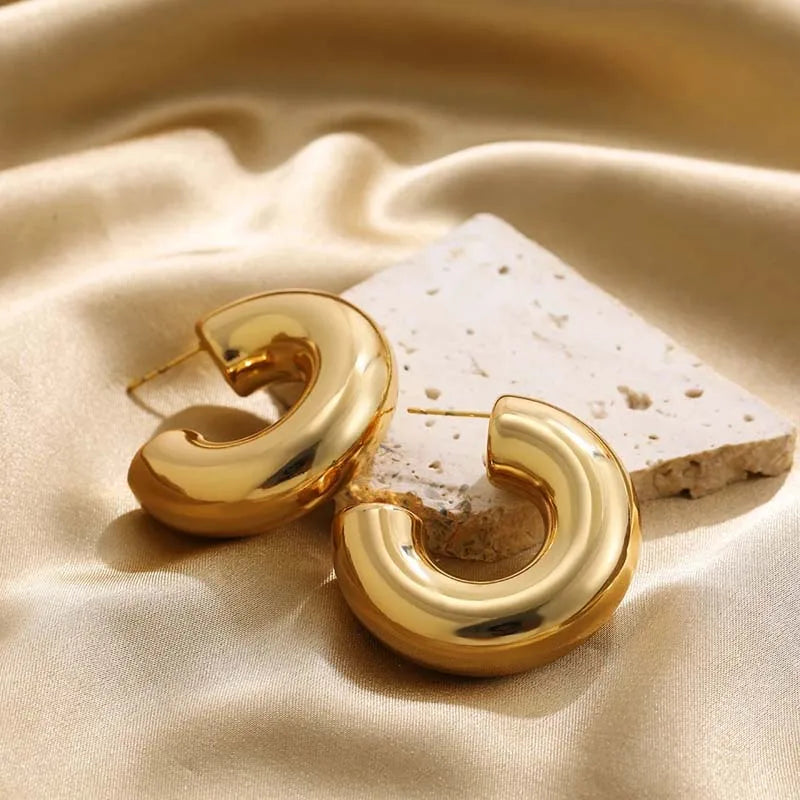 Women's elegant polished sculptural hoop earrings. Gold-tone statement jewelry for sophisticated looks.