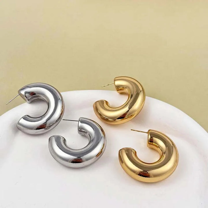 Stylish women's polished sculptural hoop earrings. Contemporary gold-plated jewelry, versatile accessory.