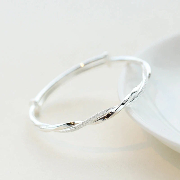 Stylish woman wearing an adjustable sterling silver bracelet with an intricate, elegant design on her wrist.