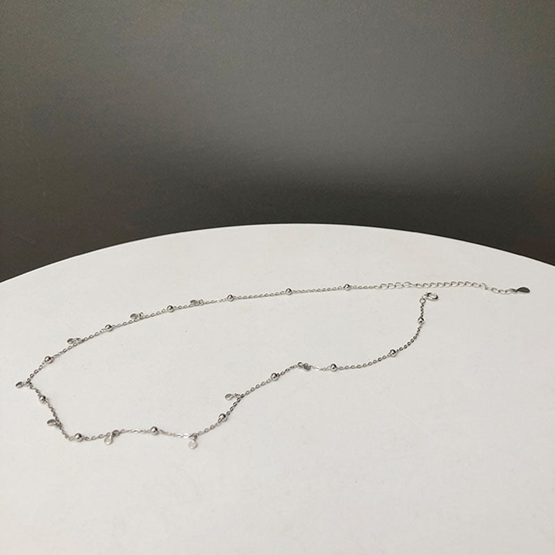 Woman wearing an elegant silver teardrop necklace, fashionable jewelry for special occasions.