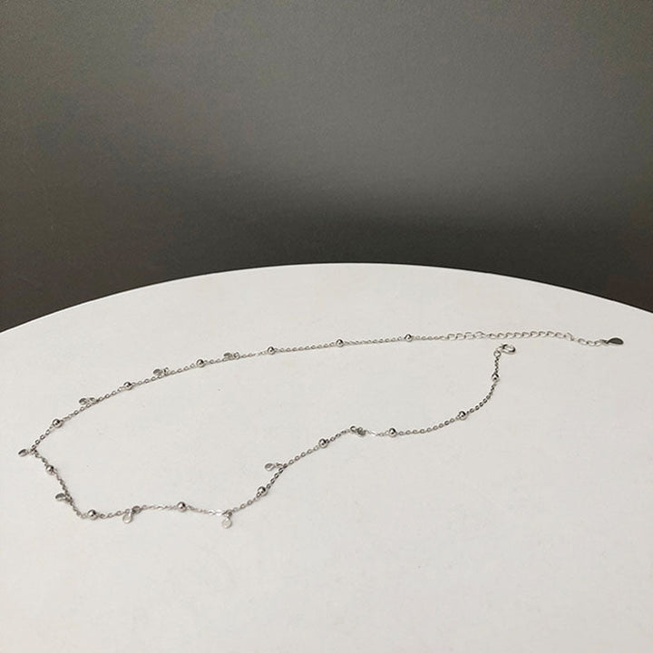 Woman wearing an elegant silver teardrop necklace, fashionable jewelry for special occasions.