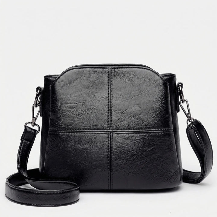 Fashionable women's stitched panel crossbody bag; a sleek, essential accessory for any outfit.