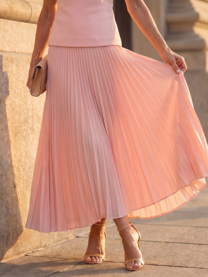 Coordinated women's outfit: sleeveless structured top and a flowing pleated maxi skirt in a rich color.