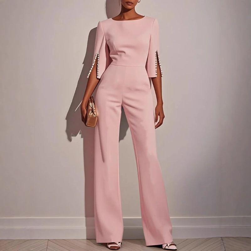 Full shot of a woman modeling a tailored evening jumpsuit with delicate pearl embellishments.