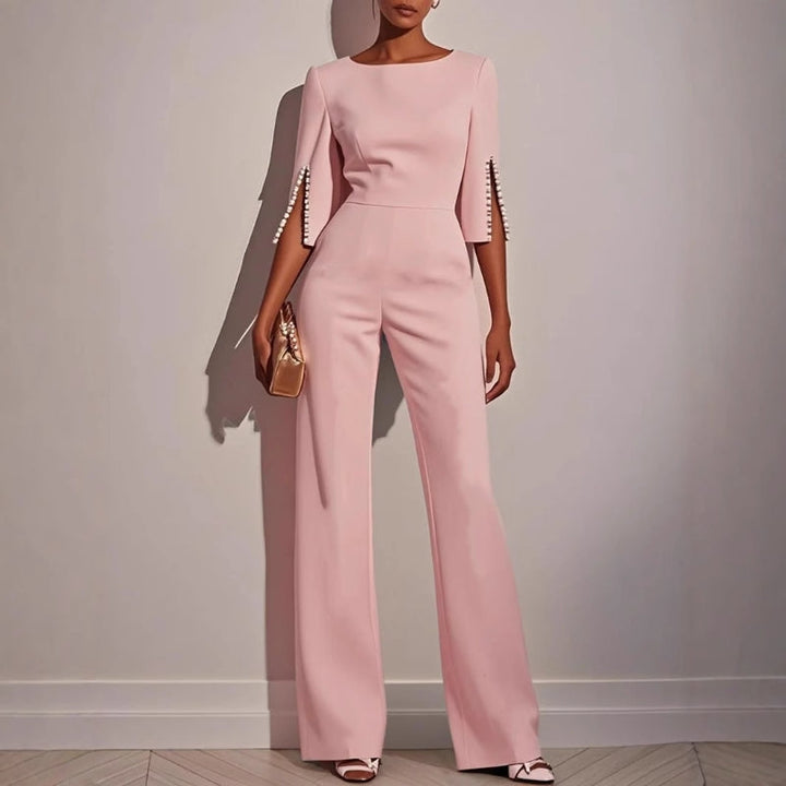 Full shot of a woman modeling a tailored evening jumpsuit with delicate pearl embellishments.