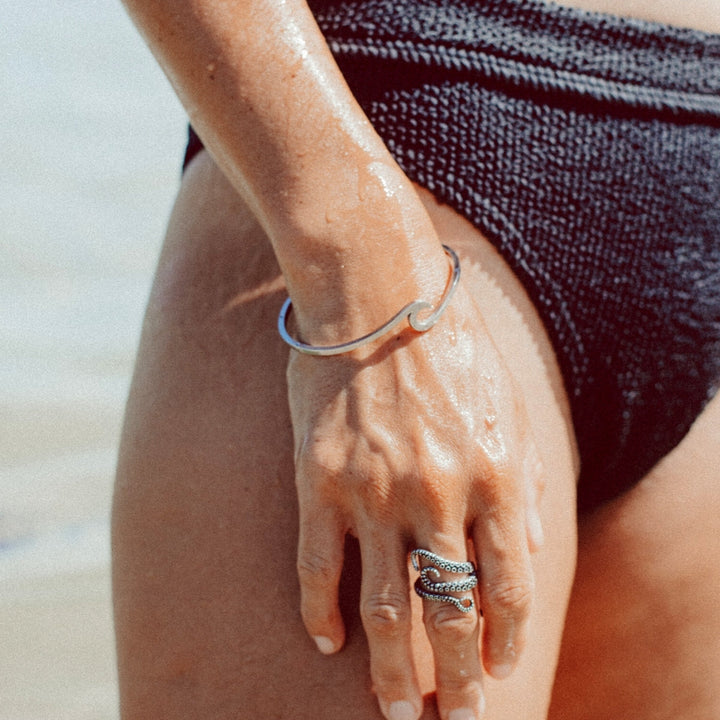 Modern women's elegant wave design bracelet. Adjustable, delicate silver & gold ocean-inspired fashion accessory.