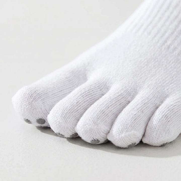 Woman wearing five-toe grip yoga socks during a pilates session. Non-slip athletic socks provide stability & comfort.