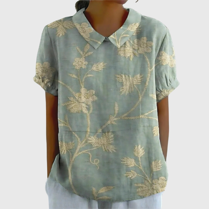 Detail shot of collared top. Vibrant floral print and button details on a women's blouse.