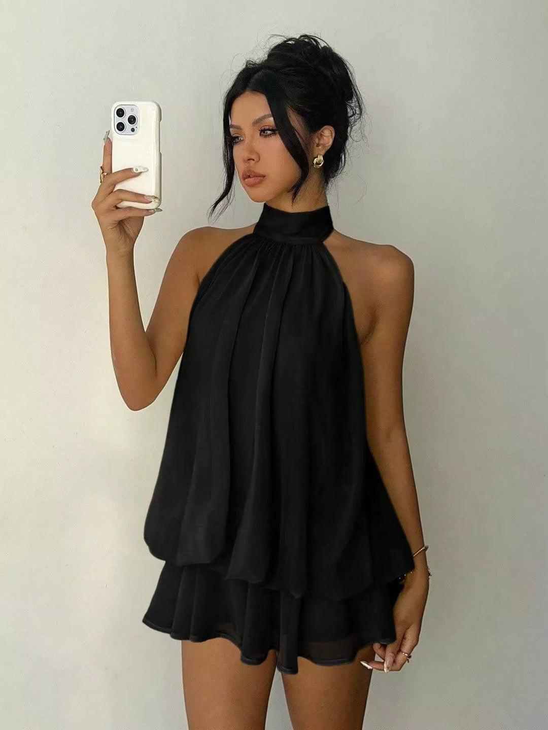 Sleeveless women's mini dress with a ruffled hem & open back, showcasing a trendy halter neckline.