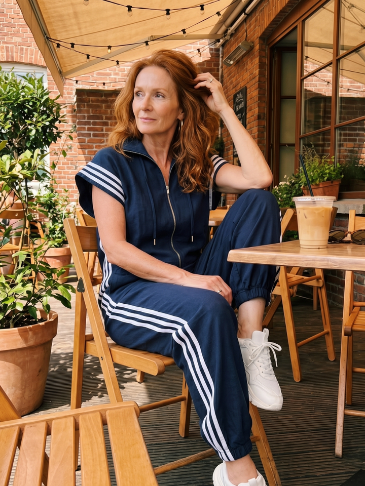 Women's full-length jumpsuit. Zip-up design, comfortable, high neck, cap sleeves, & sporty side stripes.