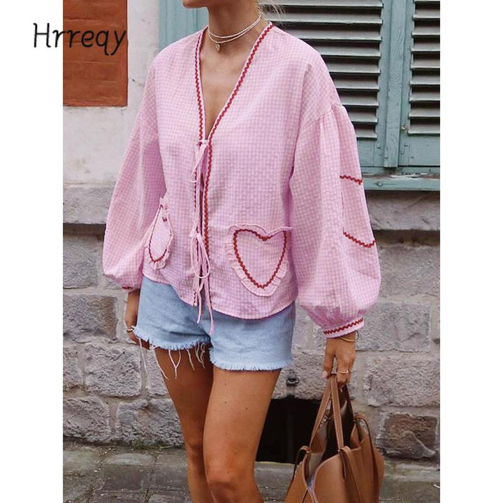 Chic women's gingham blouse. Features tie-front, heart detail, and voluminous sleeves for elegant summer fashion.
