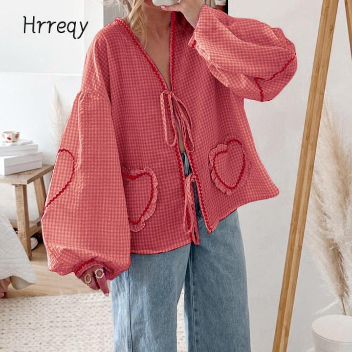 Relaxed fit women's gingham blouse with unique heart pockets, trendy tie-front, and voluminous sleeves.