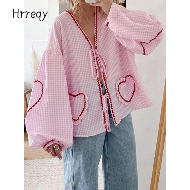 Elegant women's gingham blouse featuring a tie-front, heart pockets, and fashion-forward voluminous sleeves.