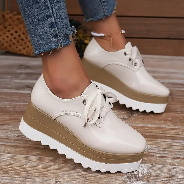 Detailed shot of the platform sole on women's glossy comfort sneakers, offering stylish height & support.