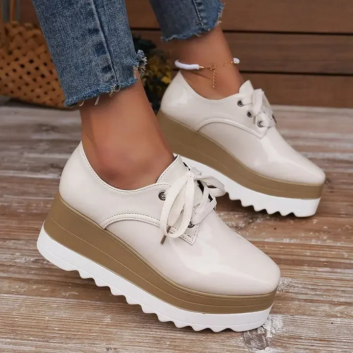 Detailed shot of the platform sole on women's glossy comfort sneakers, offering stylish height & support.