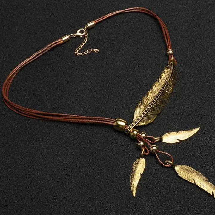 Women's gold feather necklace. Artisan-crafted boho style pendant jewelry with intricate details and a warm gold finish.