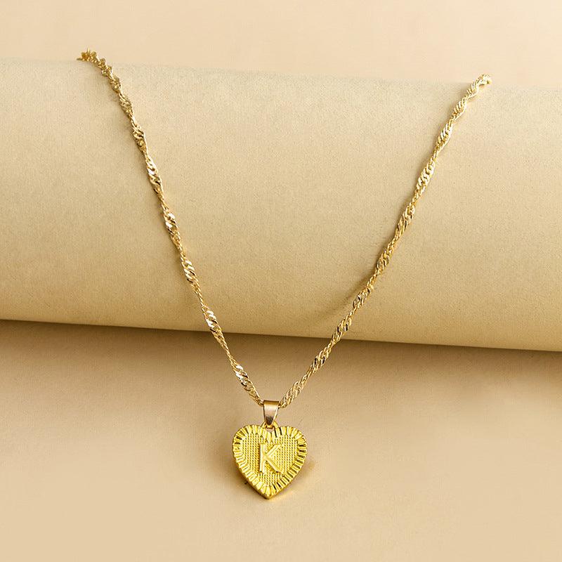 Women's personalized gold heart pendant necklace with an elegant initial.