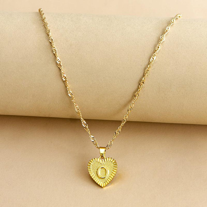 Close-up of personalized gold heart pendant with initial, elegant design.