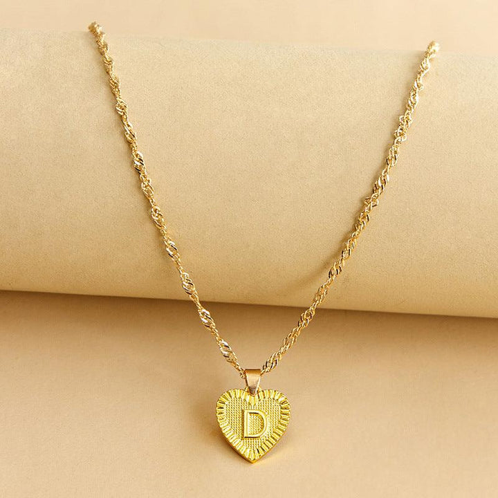 Close-up of a women's gold initial heart pendant, elegant and personalized.
