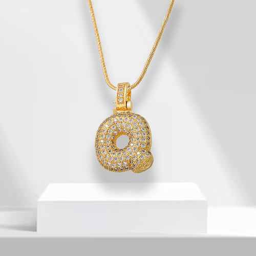 Close-up of a women's gold plated bubble letter pendant with intricate zirconia detailing.